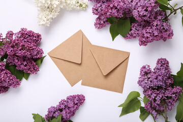 Envelopes with branches of blooming lilacs on white background. Spring concept. Top view. Flat lay
