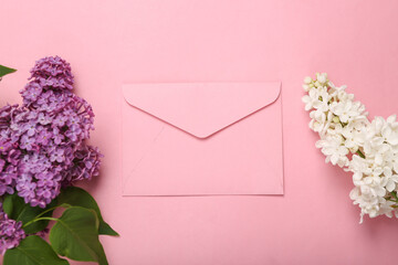 Envelope with branches of blooming lilacs on pink background. Spring concept. Top view. Flat lay