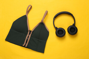sports bra and headphones on a yellow background. Fitness concept. Top view
