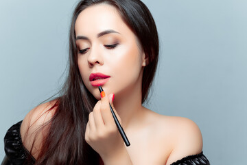 a young brunette model is applied to her lips with a lipstick pencil