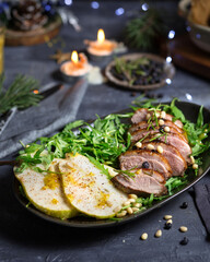 Baked duck salad with pear.A dish for the celebration of the New Year. Christmas food. Serving a New Year's dish with duck and fruit. New Year atmosphere and candles on the table