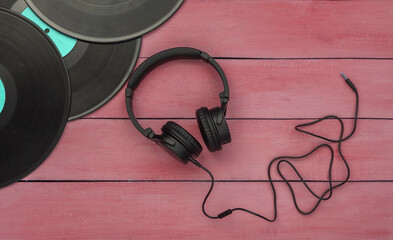 Retro vinyl records and stereo headphones on red wooden background. Top view. Flat lay