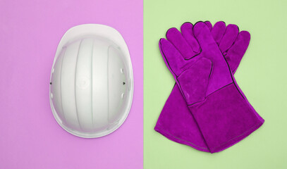 Work gloves and construction safety helmet on pink green background. Top view