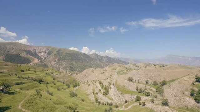 Aerial view of amazing landscape with beautiful valley on a sunny day. Action. Flying above summer mountains on blue cloudy sky background.