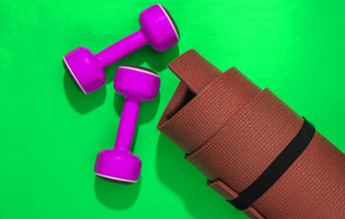 Rolled fitness mat, dumbbells on a bright green background. Healthy lifestyle, sport concept. Top view Flat lay