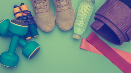 Top view composition of fitness outfit, accessories on blue background with copy space. Healthy lifestyle, sport concept.