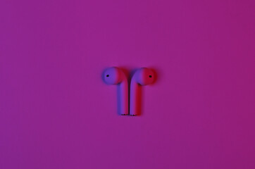 Wireless headphones in neon red blue neon gradient light.