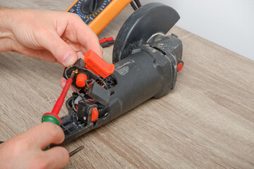 Power tool repair. An engineer repairing an angle grinder. Assembling the tool in the process of repair.