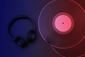 Retro vinyl records and headphones in blue red neon light. Top view
