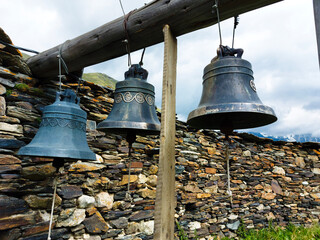 Obraz premium The old bells of Lamaria church next to the huge stone fence Ushguli Georgia.