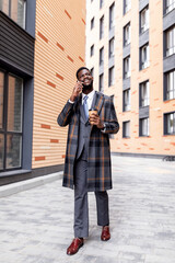 African american businessman with coffee to go having business call during break, walking outdoors