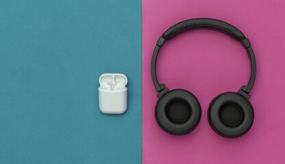 Wireless large stereo headphones and small earbuds with charger case on blue pink background. Top view