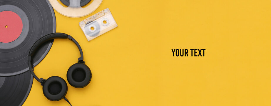 Retro vinyl records, audio magnetic reel, audio cassette and stereo headphones on yellow background. Copy space. Top view