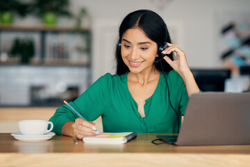 Pretty indian woman attending webinar, cafe interior, copy space