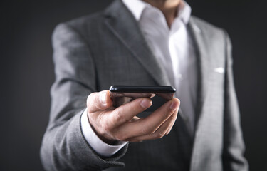 Businessman holding smartphone in office.