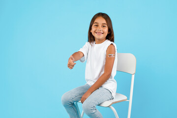 Vaccinated Little Girl Gesturing Thumbs-Up After Vaccine Shot, Blue Background