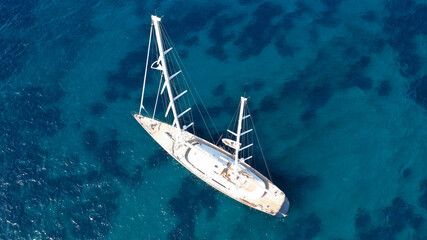 Aerial drone photo of luxury yacht anchored near famous white chalk volcanic bay of Sarakiniko, Milos island, Cyclades, Greece