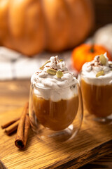 Hot and aromatic latte with pumpkin and cinnamon on a textured wooden background, copy space, on a textured board.