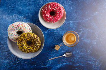 Variation of donuts. Assortment of colorful, delicious breakfast donuts, on a table top with a coffee on the side.