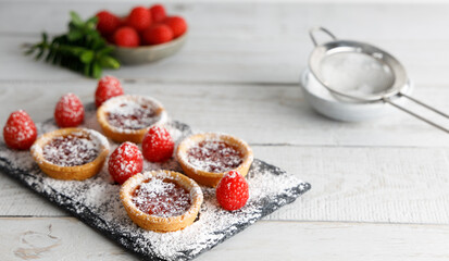 Cookie with raspberry glazing. Homemade biscuit, cookie with raspberry jam on top , on a cutting board with sugar powder glazing. Posed on a dark background.