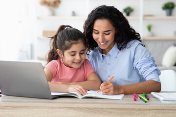 Obraz premium Homeschooling Concept. Caring Young Mom Helping With Homework To Her Little Daughter