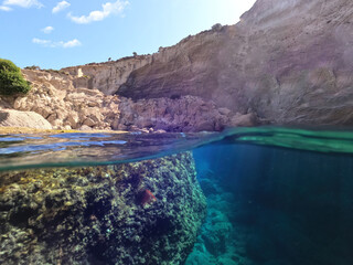 Fototapeta na wymiar Underwater split photo of beautiful deep turquoise cave of Sykia a natural volcanic white chalk round shaped open top bay, Milos island, Cyclades, Greece