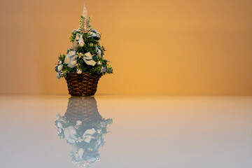 small Christmas tree with reflection on white glass table