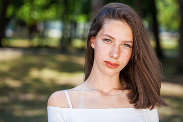 Young beautiful brown-haired girl with freckles on her face