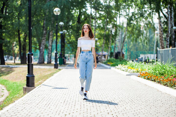 Fototapeta na wymiar Young beautiful brunette girl walking in a summer park