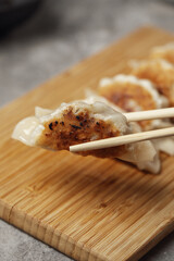 Gyoza or dumplings snack with soy sauce on wood board and grey clay background