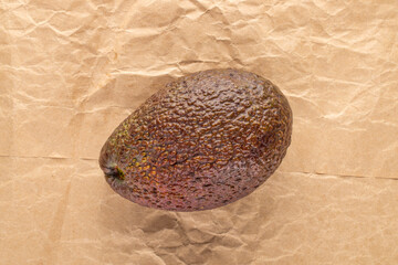 One ripe avocado on craft paper, close-up, top view.