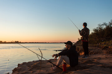 Friends fishing and having a good time on the river shore.