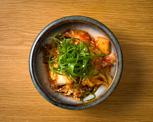 top view bowl of Kimchi, lightly spicy fermented and marinated Chinese cabbage over wooden table