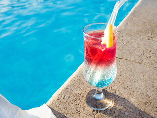 Beautiful glass with a refresh cocktail on the background of the swim pool. View from above, outdoors, close-up. Vacation and travel concept