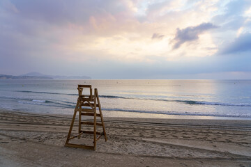 Lifeguard chair facing the sea at sunset with calm sea.