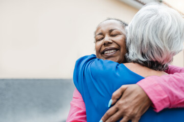 Multiracial senior women hugging each other - Elderly friendship and love concept - Focus on african woman face - obrazy, fototapety, plakaty