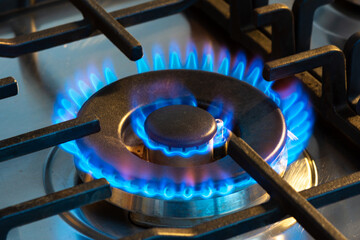 Gaz brûlant avec des flammes bleues sur le brûleur d'une cuisinière à gaz. Concept d'empreinte...