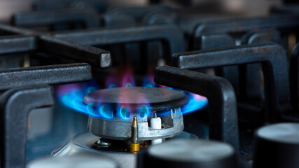 Gaz brûlant avec des flammes bleues sur le brûleur d'une cuisinière à gaz. Concept d'empreinte carbone et de prix du gaz naturel sur le marché - obrazy, fototapety, plakaty