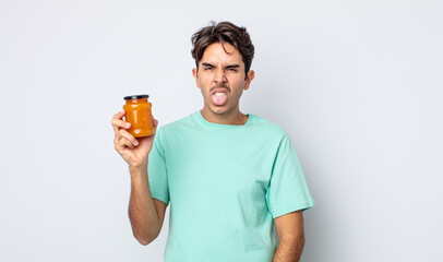 young hispanic man feeling disgusted and irritated and tongue out. peach jelly concept - obrazy, fototapety, plakaty