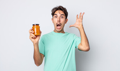 young hispanic man screaming with hands up in the air. peach jelly concept - obrazy, fototapety, plakaty