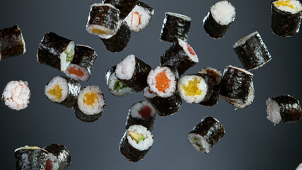 Freeze motion Shot of Fresh Sushi Flying in the Air, grey gradient background.