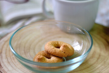 Bowl of cookies, cup, book and reading glasses on a bed. Selective focus.