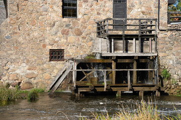 Water mill wheel rotates under a stream of water.