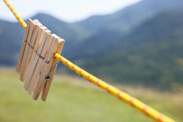 Wooden clothespins hanging on washing line in mountains, closeup