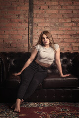 beautiful girl on a sofa made of black leather.tinted photo