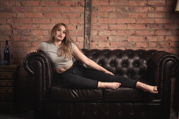 Obraz na płótnie Canvas beautiful girl on a sofa made of black leather.tinted photo