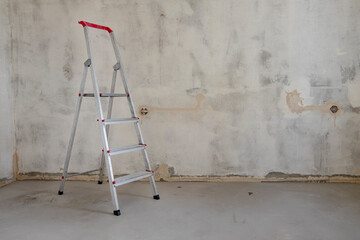 Building stepladder stands in empty room, prepared for renovation and transformation of interior....