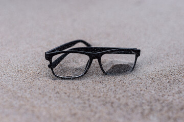 The glasses on the sand in the windy day. 