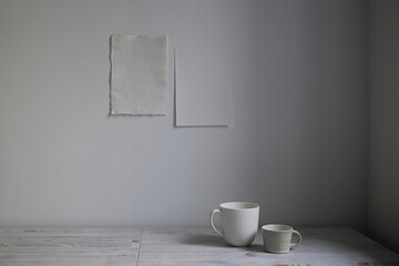 Scandinavian style. Interior Design. A white cups is on the table. Two blank sheets of paper are attached to the wall. Empty space for text