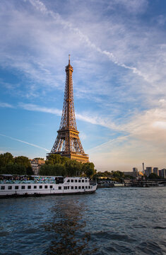 The Eiffel Tower from the River Seine with a passing tourist boat with people on board at a beautiful sunset.